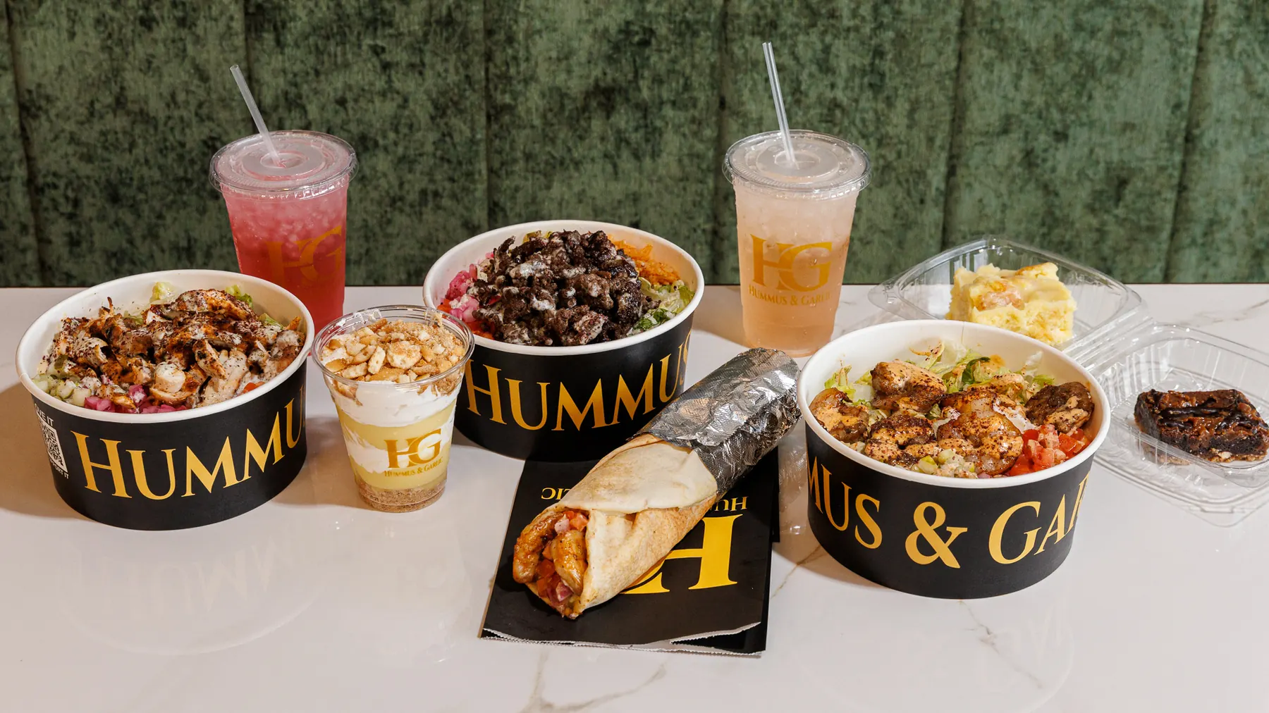 Bowls, shawarma and sides spread across a table at Hummus & Garlic